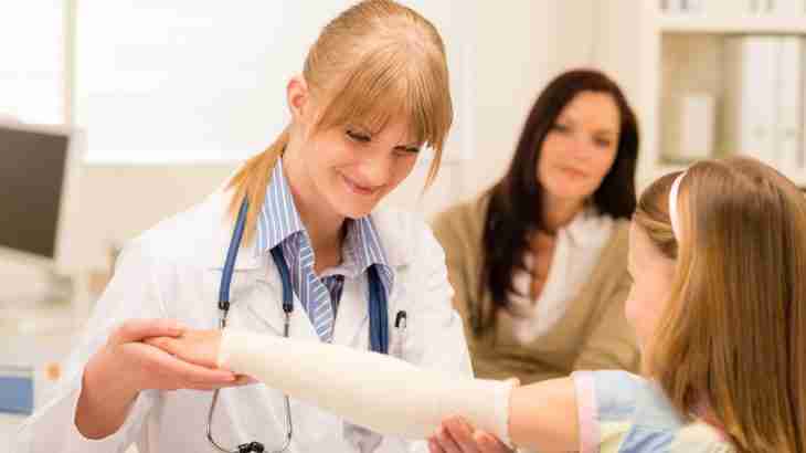 child broken arm injury being examined by doctor to help determine payout with anxious mother looking on