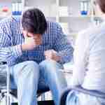 Facial Fracture Claim Accident victim in wheelchair at doctors covering face with hand to conceal facial fracture injury