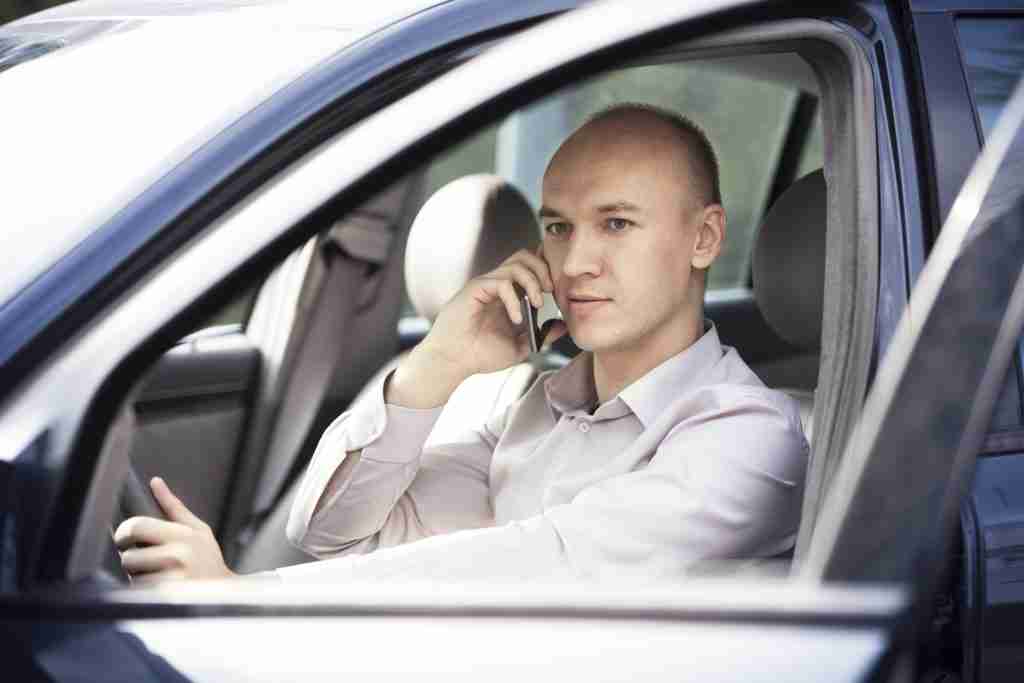Business man talking on phone and driving without seatbelt on failure to wear seatbelt