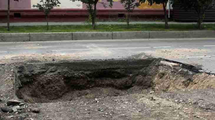 Deep unprotected road defect hole causing trip hazard