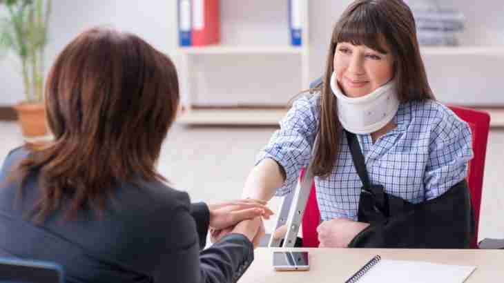 Personal injury solicitor meeting accident victim client with arm in sling and neck brace