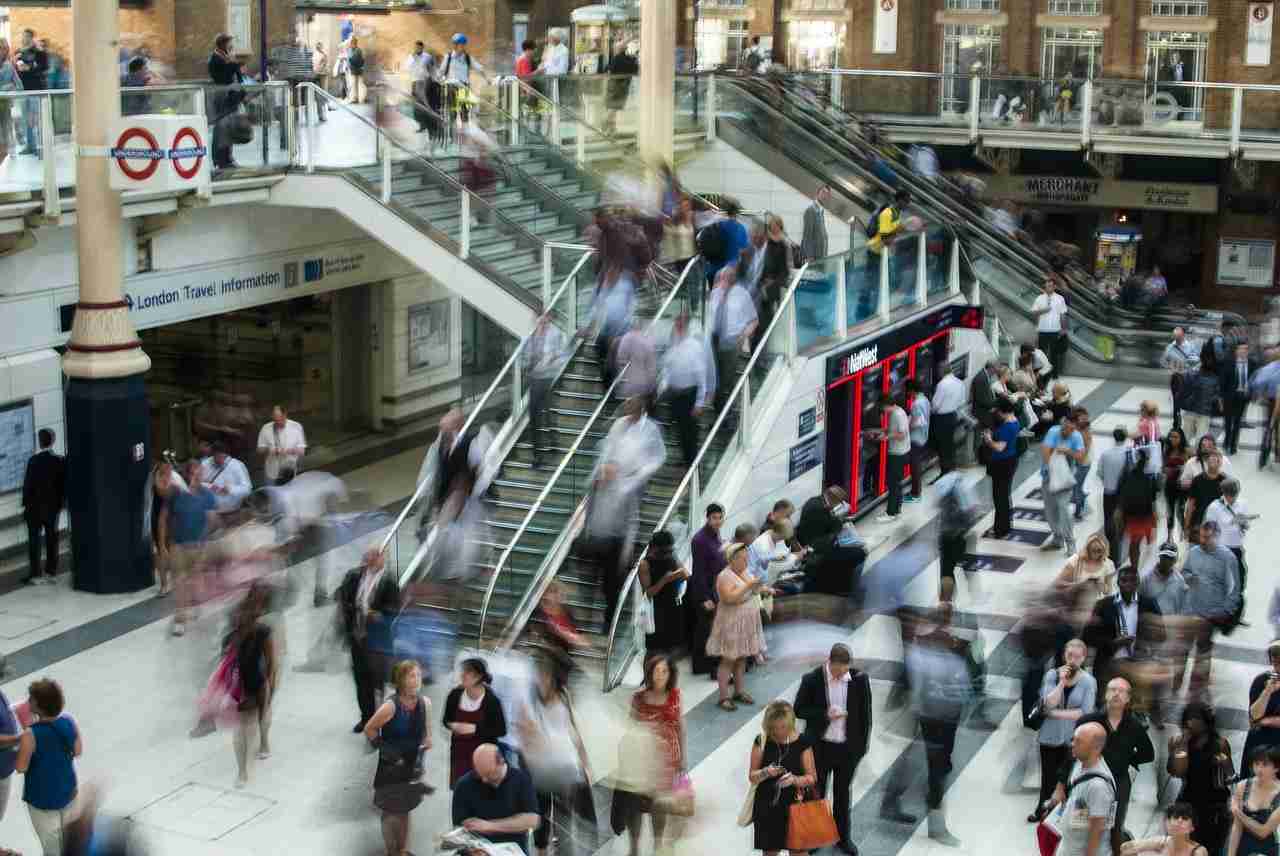 Crowded London metro station with escalators and people walking through a public concourse