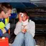 Slip Trip Injury Payouts Injured person receiving treatment from a paramedic following an accident, with facial injuries and a neck brace visible