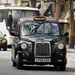 Taxi Accident Claim Black cab taxi driving on a road with pedestrians and other vehicles nearby