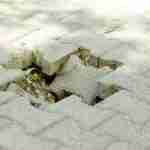What To Do After A Trip Or Fall Uneven paving stones with a significant drop creating a trip hazard on a pavement