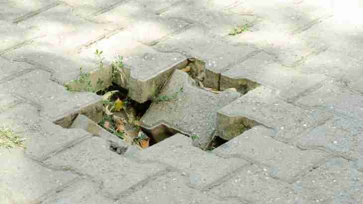 Uneven paving stones with a significant drop creating a trip hazard on a pavement